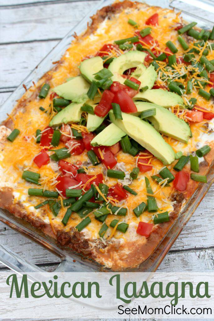 mexican lasagna casserole, topped with green avocados and scallions, and red tomato