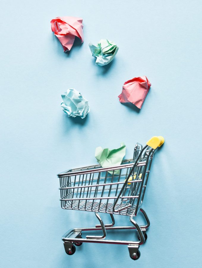 shopping  cart against blue background with colored crumpled paper
